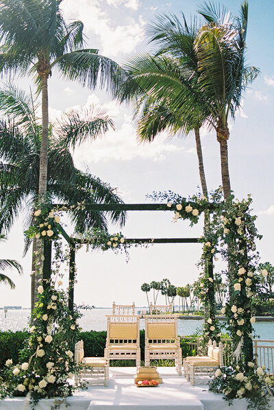 Elegant floral mandap setup framed by palm trees for a destination Indian wedding at the Ritz Carlton Sarasota — captured by Asia Pimentel Photography.