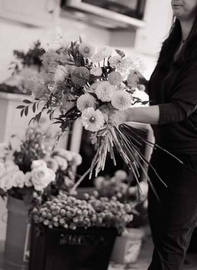 Florist carrying a large metal bucket overflowing with fresh-cut flowers