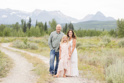 Christy with her husband and daughter outside near the mountains