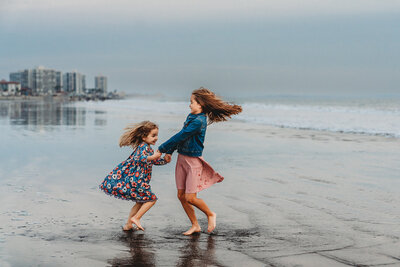 San Diego Family Photography capturing sisters playing in the water during beach family photos