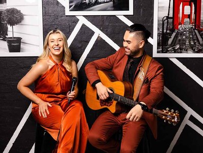 Acoustic female and male duo in formal attire with microphone and guitar