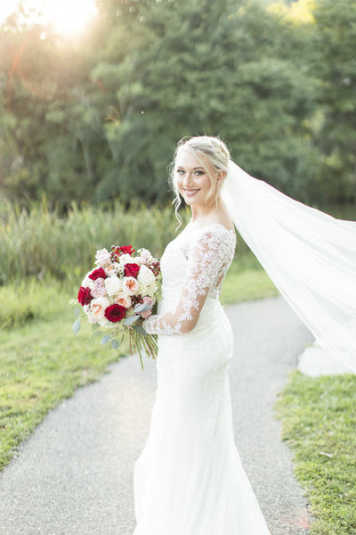 Bride holding red and pink rose bouquet
