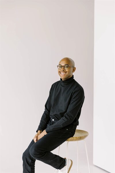 black and white photo in a black turtle neck sitting on the ground smiling of Colorado Wedding Photographer JKG Photography