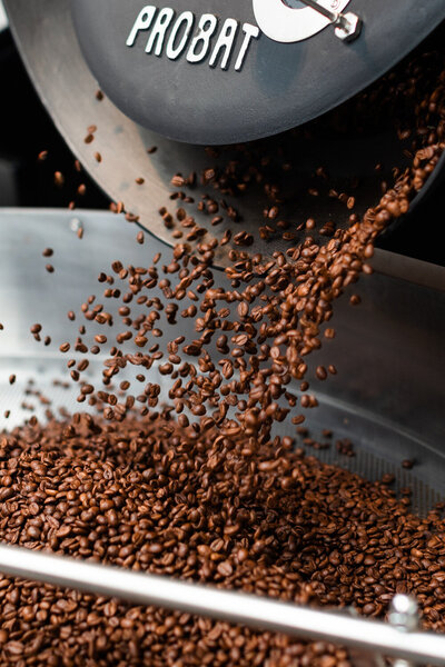 coffee beans being poured out into a pan
