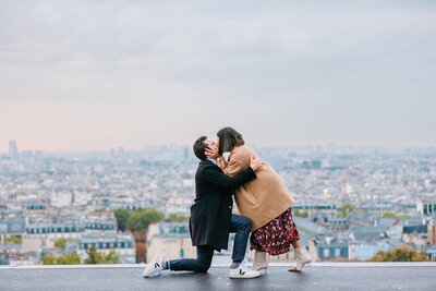 Man kneeling and kissing his partner just after proposing in front of Sacré-Cœur in Montmartre during a romantic Paris proposal photoshoot