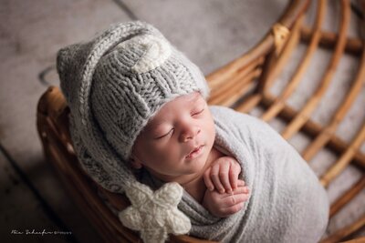 Newborn baby boy peacefully sleeping in a cozy basket, wrapped in soft blankets.