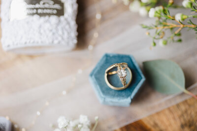 A close up of wedding and engagement rings standing up together in a ring box 