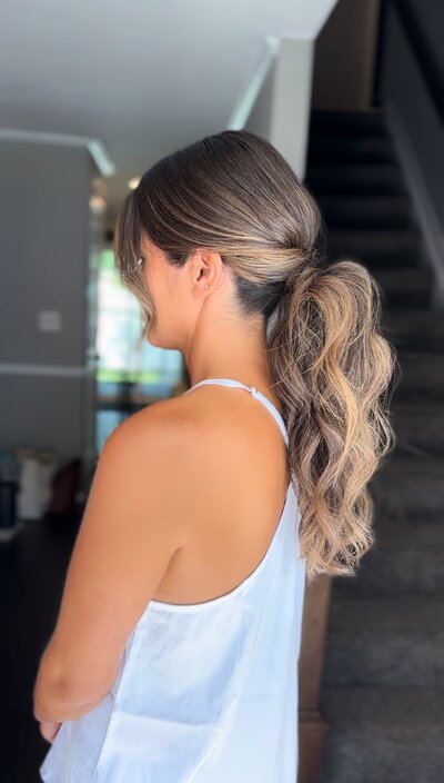 High ponytail paired with delicate, face-framing curls — trendy, feminine bridal hairstyle by Klover Beauty in Maryland.