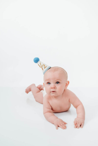 Baby boy smiles with cake during cake smash birthday session.
