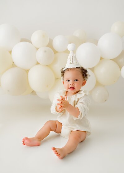baby girl sitting in front of a balloon display during a cake smash 1st birthday session