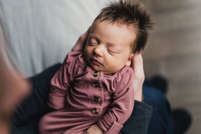 Newborn baby girl resting on parents lap with hands calming her by Seattle newborn photographer