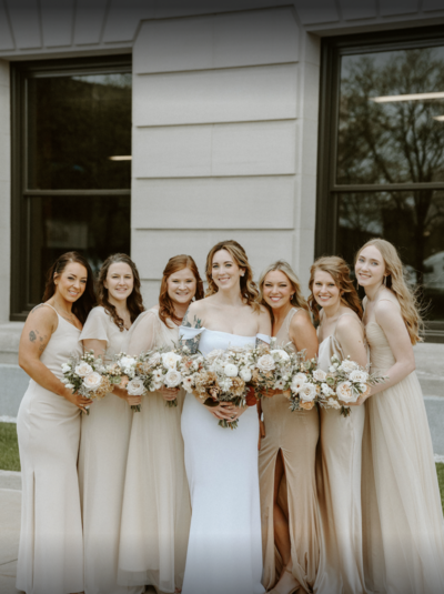 a bride and her bridal party stand in front of a building after having their bridal hair and makeup done in Indianapolis