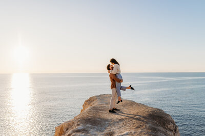 Engagement photos at the beach with the couple kissing at sunset on the cliffs. Taken at Port Willunga, South Australia but Canberra Wedding Photographer, Acacia & Grace