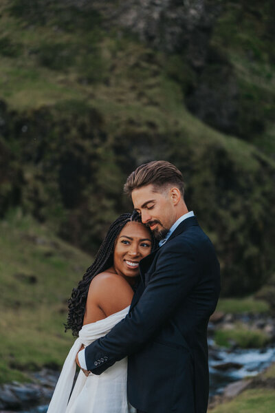 Newlyweds embrace near a creek in Iceland