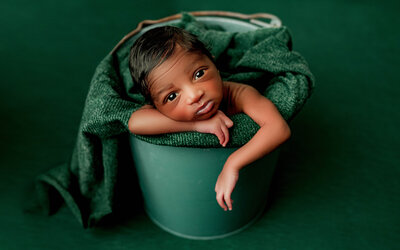 Cute newborn in emerald green bucket