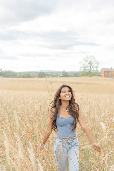 girl playing in tall grass during Manassas, VA senior picture