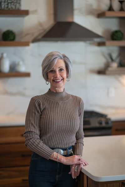 woman in a brown sweater smiling in a kitchen