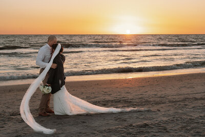 happy couple embracing on beach at sunset on their wedding day