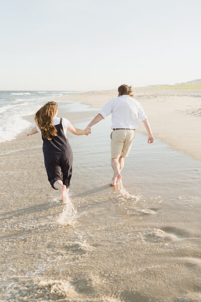 Engaged couple runs through the ocean waves in Ocean City, NJ.