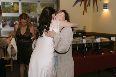 Emotional welcome-party moment with the bride hugging a guest at a Colorado wedding weekend event