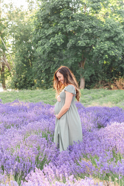 Expecting mom holding her baby bump in a field of lavender for maternity photos in st george utah