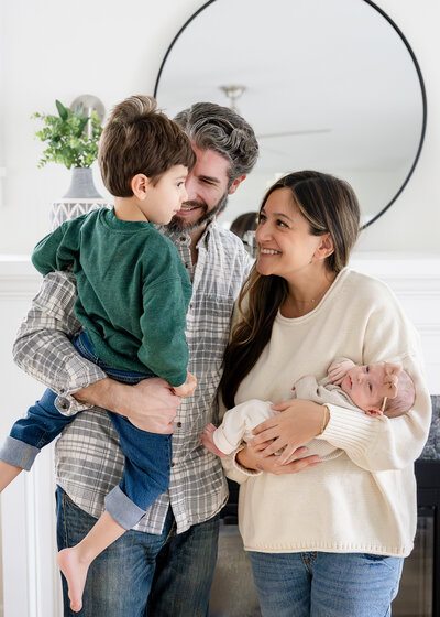 Family hugs and smile at each other at a lifestyle family newborn photo session.