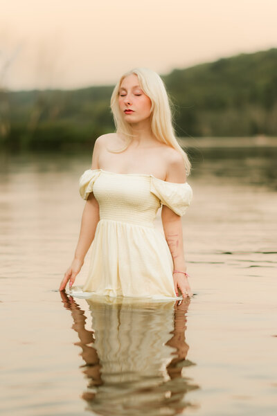 Artistic senior portrait of a young woman standing in water during sunset in Minneapolis, captured by Shannon Kathleen Photography in a natural light outdoor session.