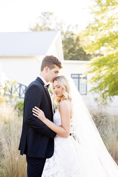 Bride and groom sharing a kiss in a sunny Alabama field — Madison Abernathy Photo