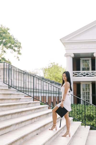 College senior walking up steps with graduation hat