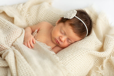 a newborn baby sleeping in a warm white blanket by Bucks County Photographer Ivory Tree Portraits.