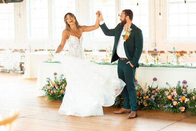 Bride twirling in her wedding dress while holding groom's hand