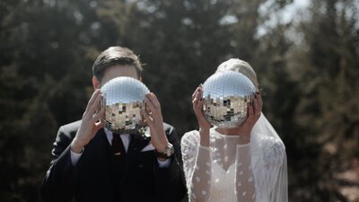 bride and groom holding disco balls