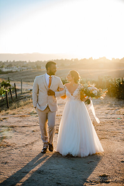 bride and groom walking with linked arms down a dirt road