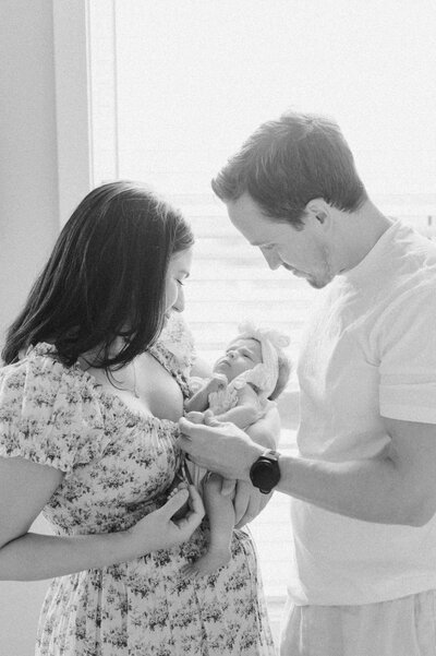 Parents share a quiet moment with their newborn baby, photographed in natural light by a Northern Virginia family photographer.