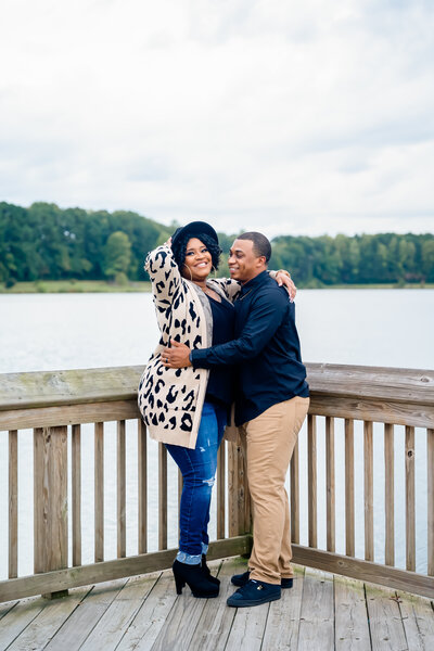 Happy couple embrace on a pier by the lake