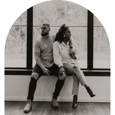 Couple sitting on a window sill looking off in the distance