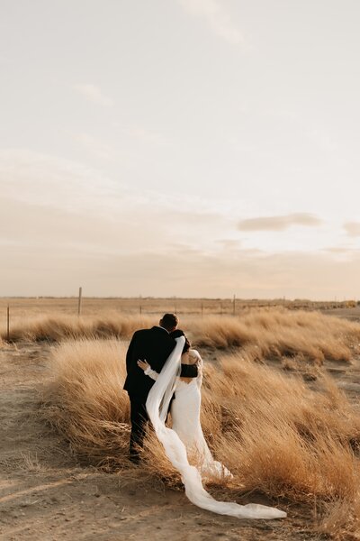 bride and groom side hugging watching the sunset
