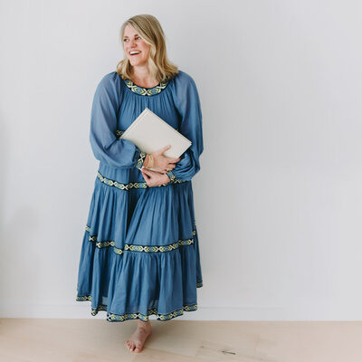 Natasha Sewell in a dress holding an heirloom album