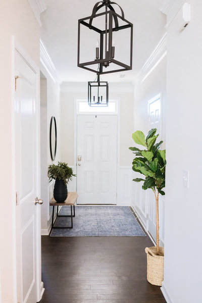 an entryway with chandeliers, rugs, and plants