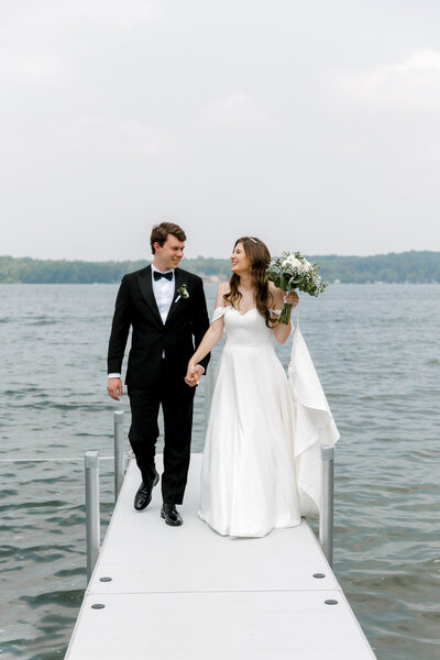 bride and groom walking along the dock in gun lake