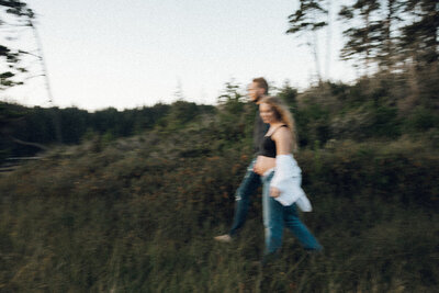 Blurry maternity photo of couple walking together on the Oregon coast during blue hour. 