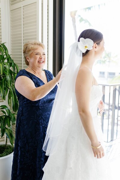 A parent smiling a their child in a wedding dress 