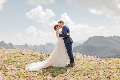 This breathtaking photograph captures the bride and groom sharing a romantic kiss on top of a mountain after their helicopter wedding ceremony and vows. The stunning alpine landscape adds to the beauty and adventure of the moment, making it a truly unforgettable celebration.