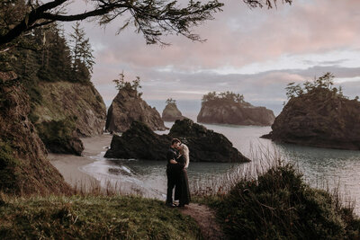 An eloping couple wearing all black, kissing at Secret Beach in Samuel H Boardman Scenic Corridor in Oregon.