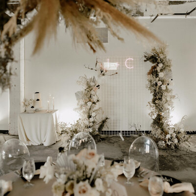 wedding reception with modern ghost chairs, dried florals, and a sleek chic cake