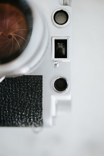 Close-up of a professional camera resting on a table with natural light and creative styling.