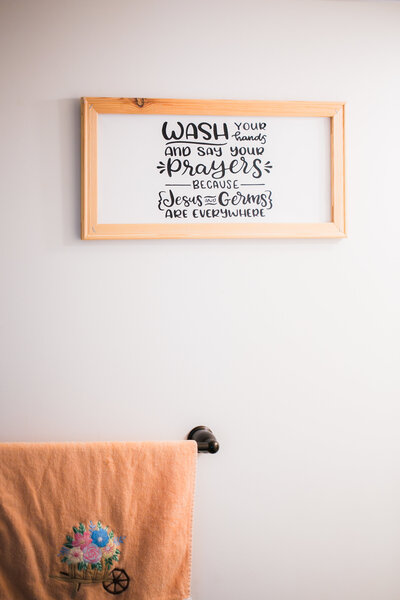 Rustic wooden-framed sign reading “Wash your hands and say your prayers” above embroidered towel, handcrafted home sign by Cobero Collective.