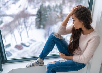 Woman looking sad staring out window