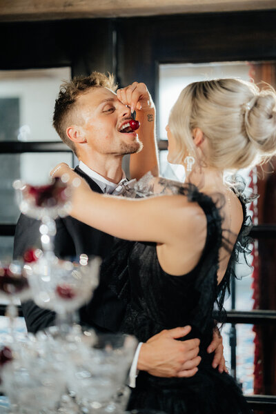 Wife feeds husband cherry from champaign tower at Royal Palms Scottsdale wedding