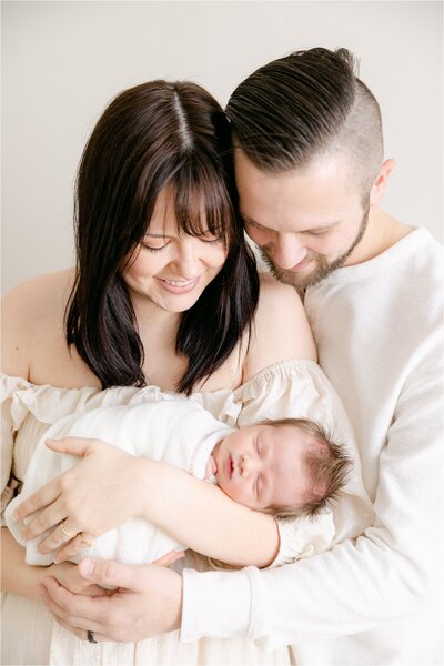 Mother and father look down at newborn baby boy being held in mother's arms, Indianapolis newborn photographer